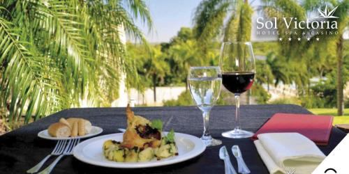 a table with two plates of food and a glass of wine at Sol Victoria Hotel SPA & Casino in Victoria