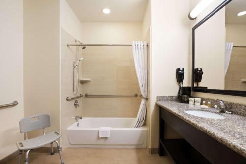 a bathroom with a bath tub and a sink at Days Inn & Suites by Wyndham Galveston West/Seawall in Galveston
