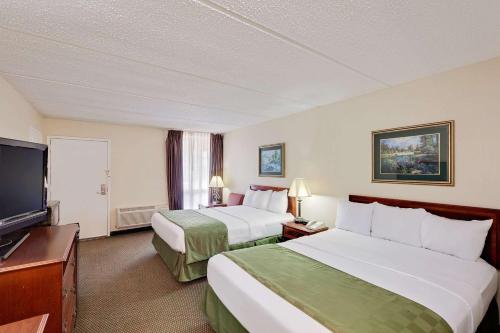 um quarto de hotel com duas camas e uma televisão de ecrã plano em Days Inn by Wyndham Bay City em Bay City