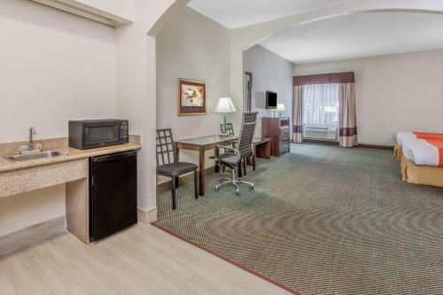 a hotel room with a bed and a desk with a television at Days Inn & Suites by Wyndham Pasadena in Pasadena