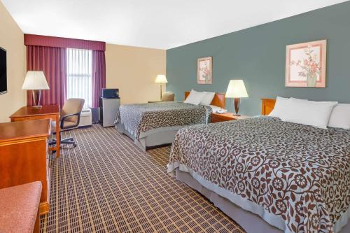 A bed or beds in a room at Days Inn & Suites by Wyndham Kalamazoo