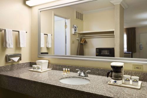 a bathroom with a sink and a large mirror at Days Inn & Suites by Wyndham Trinidad in Trinidad