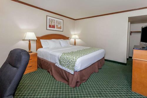 a hotel room with a bed and a television at Days Inn & Suites by Wyndham Warren in Warren