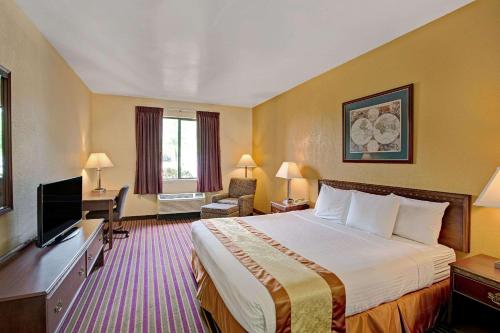 een hotelkamer met een bed en een flatscreen-tv bij Days Inn & Suites by Wyndham Hickory in Hickory