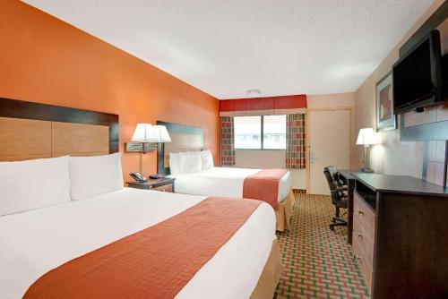 a hotel room with two beds and a flat screen tv at Days Inn by Wyndham Independence in Independence