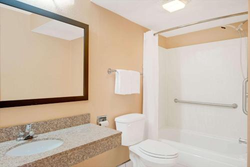 a bathroom with a sink and a toilet and a mirror at Days Inn by Wyndham Independence in Independence