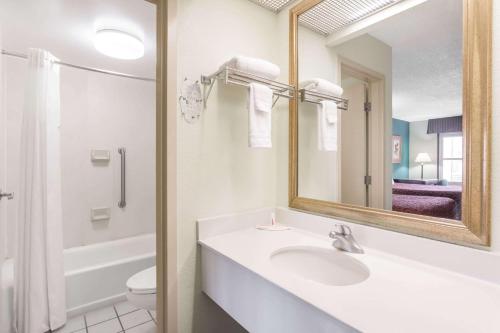 a bathroom with a sink and a mirror and a toilet at Days Inn by Wyndham Marianna in Marianna