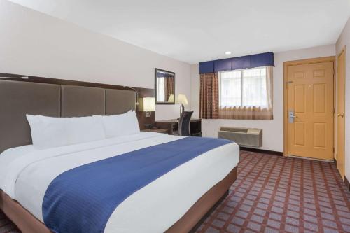 Habitación de hotel con cama grande y escritorio. en Days Inn by Wyndham Woodbury Long Island en Woodbury