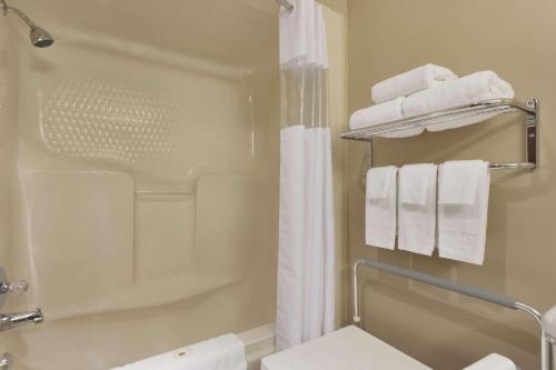 y baño con ducha y toallas blancas. en Days Inn by Wyndham Dalhousie, en Dalhousie