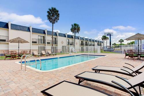 una piscina con sedie a sdraio e un hotel di Days Inn & Suites by Wyndham Tampa - Ybor City a Tampa