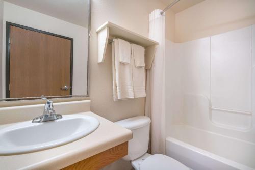 Baño blanco con lavabo y aseo en Days Inn & Suites by Wyndham Rochester South, en Rochester