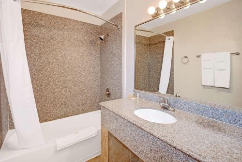W łazience znajduje się umywalka, wanna i lustro. w obiekcie Days Inn by Wyndham Albuquerque Downtown w Albuquerque