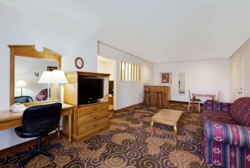 a hotel room with a couch and a desk and a television at Days Inn by Wyndham San Angelo in San Angelo