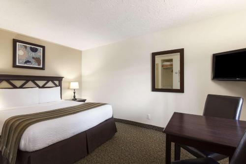 a hotel room with a bed and a desk and a television at Days Inn by Wyndham Montreal East in Montréal
