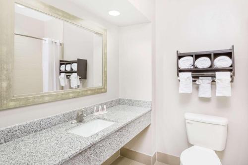 een badkamer met een wastafel, een spiegel en een toilet bij Days Inn & Suites by Wyndham Madisonville in Madisonville