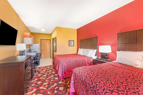 a hotel room with two beds and a flat screen tv at Days Inn & Suites by Wyndham El Dorado in El Dorado