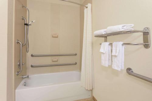 a bathroom with a shower and a bath tub with towels at Days Inn by Wyndham Semmes Mobile in Mobile