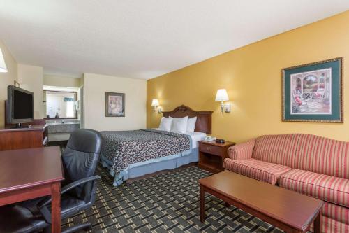 Pokój hotelowy z łóżkiem, biurkiem i kanapą w obiekcie Days Inn & Suites by Wyndham Warner Robins Near Robins AFB w mieście Warner Robins