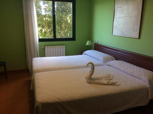 Una habitación con dos camas con un cisne. en Hotel Brisamar, en Bañugues