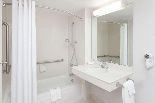 bagno bianco con lavandino e specchio di Days Inn & Suites by Wyndham Arlington Heights ad Arlington Heights