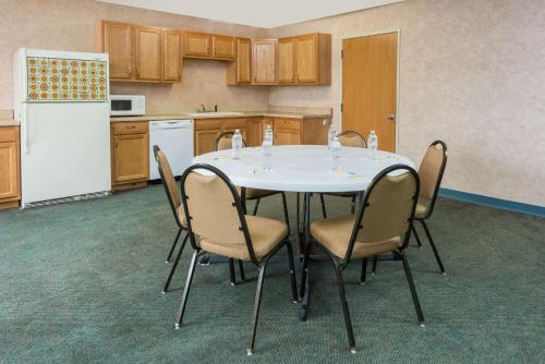 une cuisine avec une table avec des chaises et un réfrigérateur dans l'établissement Days Inn by Wyndham Osage Beach Lake of the Ozarks, à Osage Beach