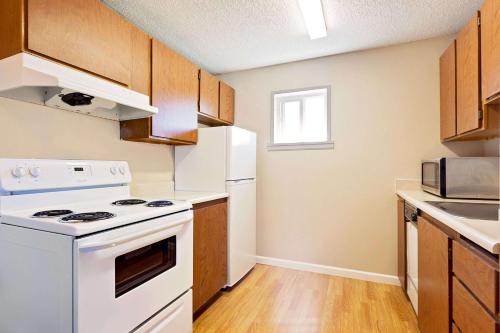 a kitchen with white appliances and wooden cabinets at Days Inn by Wyndham Lakewood South Tacoma in Lakewood