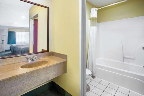 a bathroom with a sink and a toilet and a mirror at Days Inn by Wyndham Abbeville in Abbeville