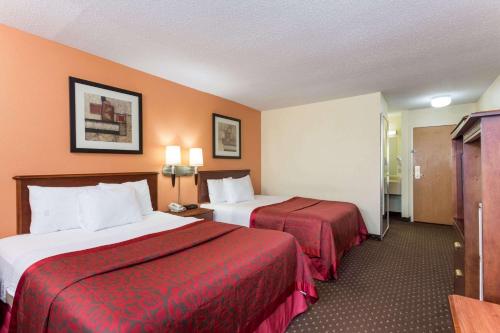Habitación de hotel con 2 camas con sábanas rojas en Days Inn & Suites by Wyndham Bloomington/Normal IL, en Bloomington
