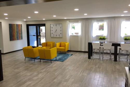 a room with yellow chairs and a table and a clock at Days Inn & Suites by Wyndham Cincinnati North in Springdale