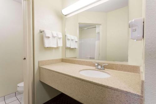 a bathroom with a sink and a mirror at Days Inn & Suites by Wyndham Bloomington/Normal IL in Bloomington