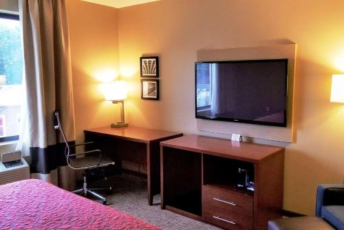 a hotel room with a television and a desk with a bed at Days Inn by Wyndham Brooklyn Marine Park in Brooklyn