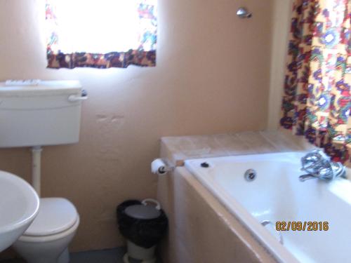 a bathroom with a tub and a toilet and a sink at Toad Tree Cabins in Sodwana Bay