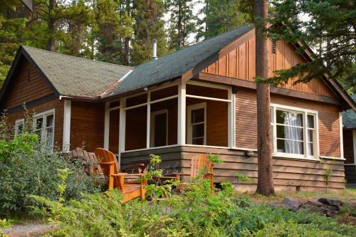 een klein houten huis in het bos met een veranda bij Johnston Canyon Lodge & Bungalows in Castle Junction