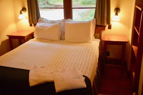 a bedroom with a bed with white sheets and a window at Johnston Canyon Lodge & Bungalows in Castle Junction