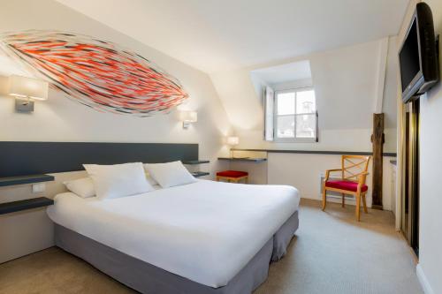 a bedroom with a large white bed and a chair at Hotel Restaurant Le Dauphin et Le Spa du Prieuré in Caen