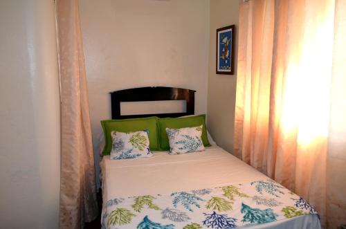 a small bedroom with a bed with green and blue pillows at Sosua Sweet Vacations in Sosúa
