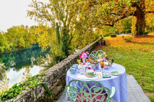 a blue table with dolls on it next to a river at La Rebière d'Or, B&B et Gîte in Mouleydier