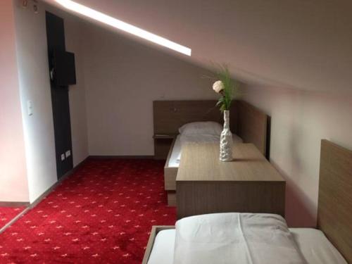 Cette chambre comprend 2 lits et un vase avec une fleur. dans l'établissement Gasthof Falter, à Straubing