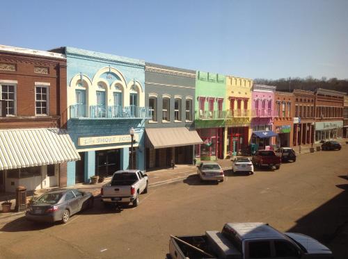 eine Stadtstraße mit Autos, die vor den Gebäuden geparkt sind in der Unterkunft The Main Street Hotel in Yazoo City