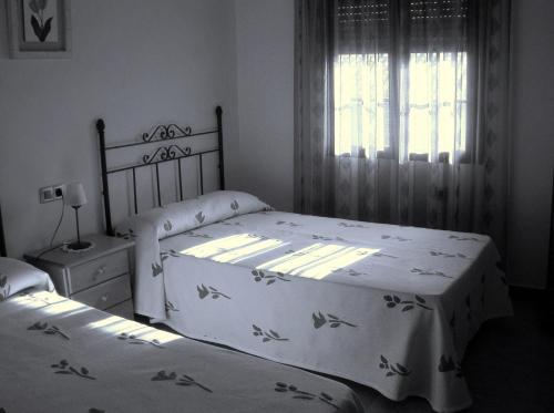 a bedroom with two beds and a window at Posada La Reja in Malpica