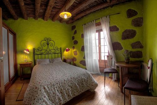 um quarto verde com uma cama e uma janela em Geranios Rojos em Las Rosas