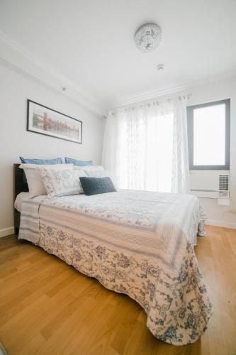 a white bedroom with a large bed and a window at New York Suite at Oasis in Cagayan de Oro