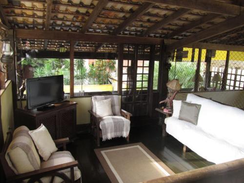 a living room with a couch and a tv at Pousada Lugar Comum in Boicucanga