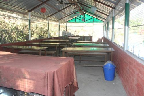 um pátio com mesas e bancos num edifício em Natural Camps with InHouse Swimming Pool em Rishikesh