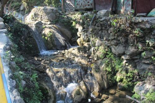 a waterfall in a garden with rocks and plants at Natural Camps with InHouse Swimming Pool in Rishīkesh