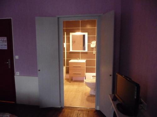a room with a bathroom with a toilet and a mirror at Hôtel du Commerce in Semur-en-Auxois