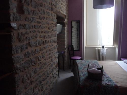 a living room with a brick wall and a chair at Hôtel du Commerce in Semur-en-Auxois