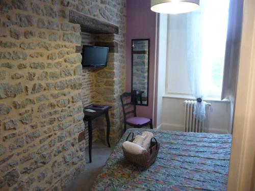 a bedroom with a bed and a brick wall at Hôtel du Commerce in Semur-en-Auxois