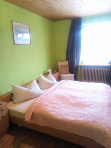 a bedroom with a bed with white sheets and a window at Pension Waldblick in Spiegelau