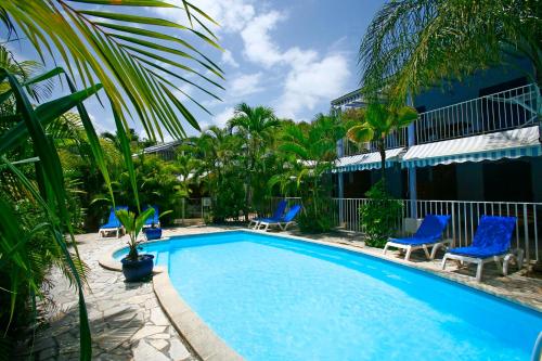 una piscina in un resort con sedie blu e palme di Blue Paradise a Le Gosier